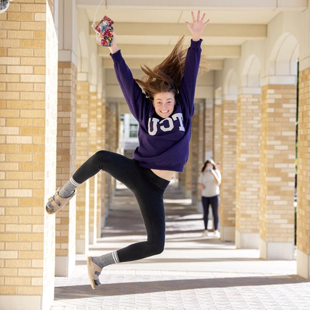 TCU student jumps for joy in the Commons